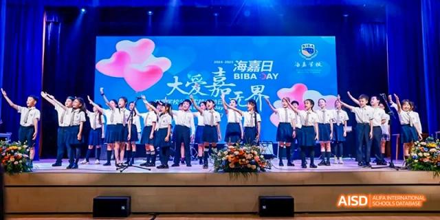 Students performing on a stage in front of a banner at Beijing International Bilingual Academy.