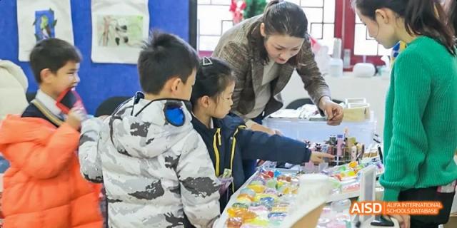 A student focused on a task while sitting at a desk with other students in the background at Beijing International Bilingual Academy.