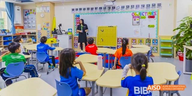 A teacher standing at the front of a classroom of young students who are sitting at their desks at Beijing International Bilingual Academy.