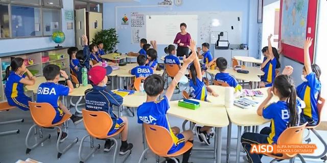 Students in a classroom, with one student raising his hand, at Beijing International Bilingual Academy.