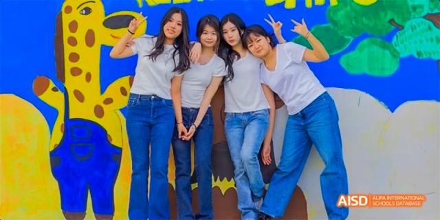 A group of students smiling and posing for a photo, all wearing blue jeans at Beijing International Bilingual Academy.