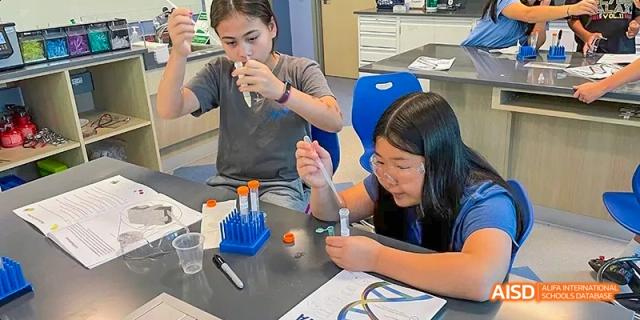 Two students working with scientific equipment in a lab at Beijing International Bilingual Academy.