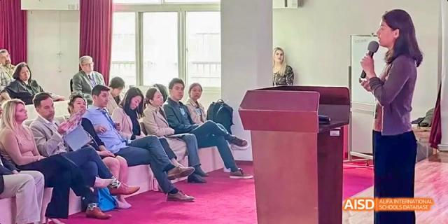 A group of adults and students sitting in a formal meeting or conference room at Beijing International Bilingual Academy.