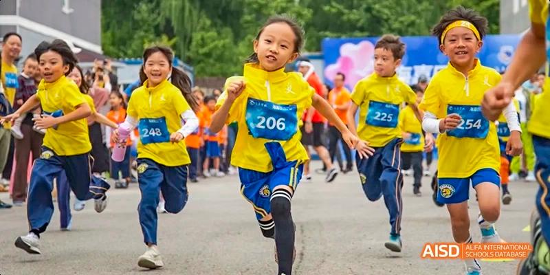 A group of students in yellow and blue shirts running a race at Beijing International Bilingual Academy.