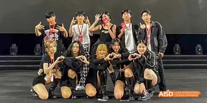 A group of students in black outfits posing with their hands to form a heart shape at Beijing International Bilingual Academy.