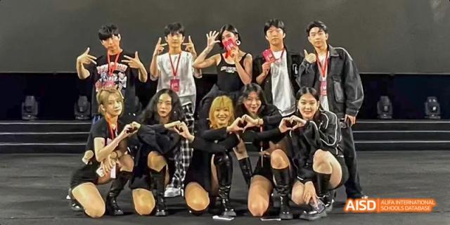 A group of students in black outfits posing with their hands to form a heart shape at Beijing International Bilingual Academy.