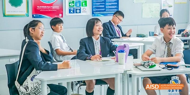 A female student and an adult in a classroom, with the adult smiling and talking at Beijing International Bilingual Academy.