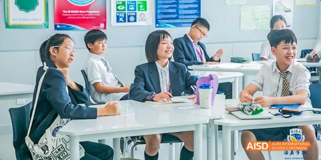 A female student and an adult in a classroom, with the adult smiling and talking at Beijing International Bilingual Academy.