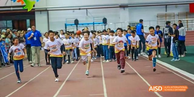 A large group of students in white shirts running on a track at Beijing International Bilingual Academy.