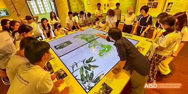 A group of students gathered around a large interactive display table at Beijing International Bilingual Academy.