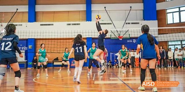 A female student jumping to spike a volleyball during a game at Beijing International Bilingual Academy.