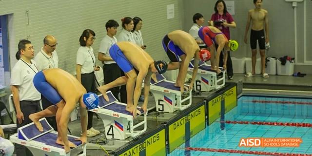 Swimmers in a starting position on the blocks at a swimming competition at Beijing International Bilingual Academy.