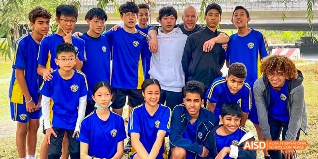 A group of male students posing for a photo with a coach or teacher at Beijing International Bilingual Academy.