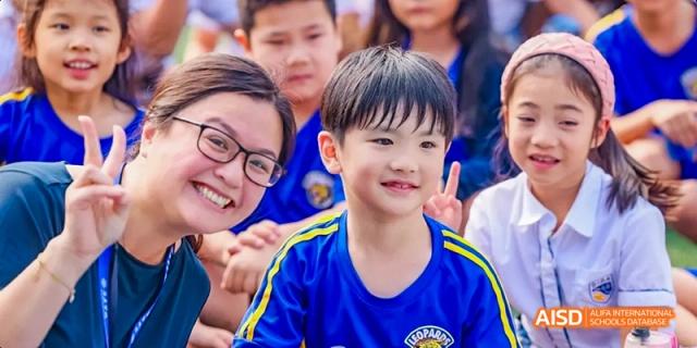 A smiling adult and a young boy in a blue shirt posing for a photo at Beijing International Bilingual Academy.