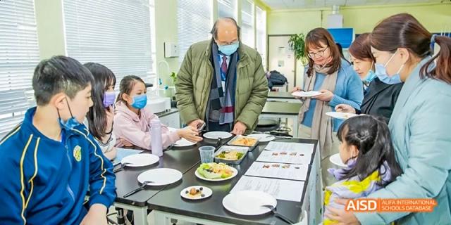 People are serving themselves from a buffet line in the dining area at Beijing International Bilingual Academy.