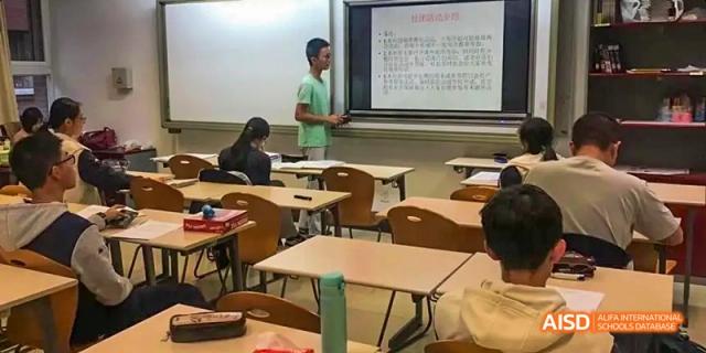 A student from Beijing National Day School International Department seated alone at a desk in a classroom.