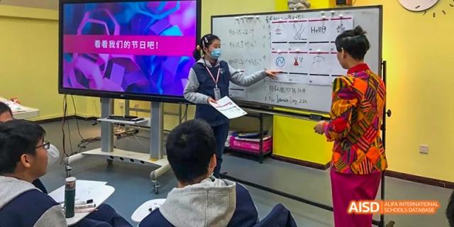 Students from Beijing National Day School International Department working on a project with a laptop in a classroom.