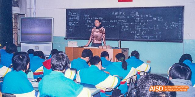 A teacher from Beijing National Day School International Department teaching a lesson at a chalkboard.