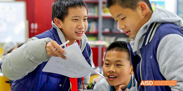 Students from Beijing National Day School International Department smiling while working on an assignment together.