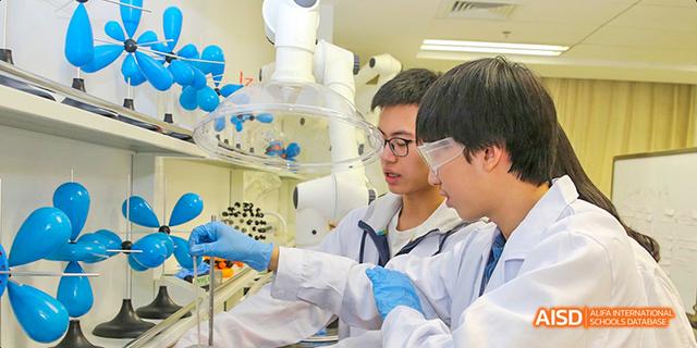 Students from Beijing National Day School International Department wearing lab coats and goggles, performing a science experiment.
