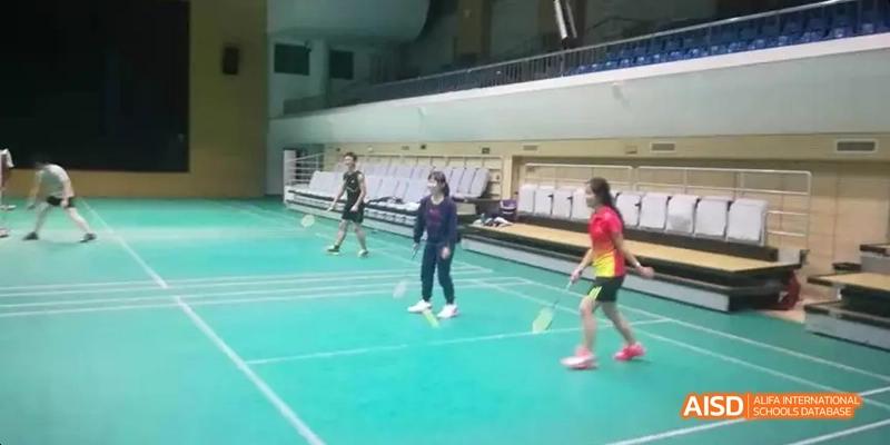 Students from Beijing National Day School International Department playing frisbee or another sport on a green court.