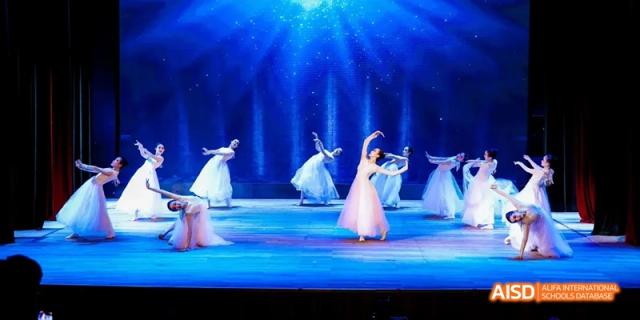 Students from Beijing National Day School International Department performing a dance on a stage.