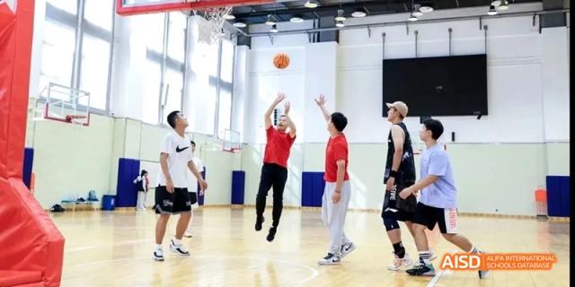 Students from Beijing National Day School International Department playing basketball in an indoor court.