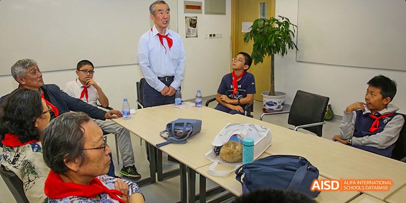 An instructor or teacher from Beijing National Day School International Department speaking to a group of people in a meeting room.