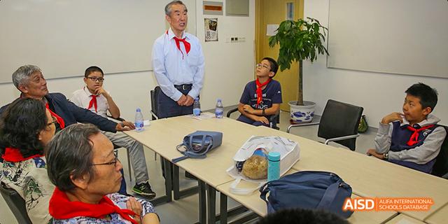 An instructor or teacher from Beijing National Day School International Department speaking to a group of people in a meeting room.