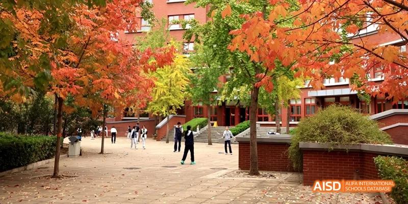 An autumn view of the campus grounds at Beijing National Day School International Department with students walking among the buildings.