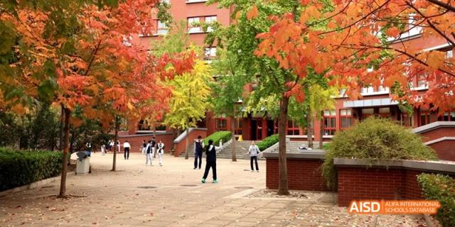 An autumn view of the campus grounds at Beijing National Day School International Department with students walking among the buildings.