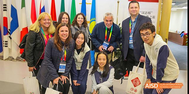 A group of students and adults from Beijing National Day School International Department posing for a photo at an event.