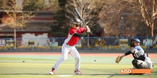 A student from Beijing National Day School International Department playing baseball during a game.