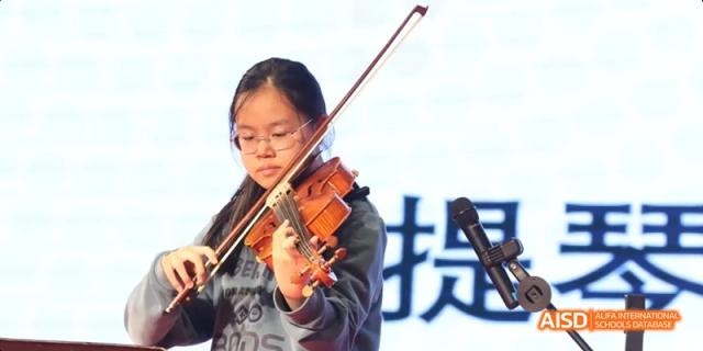 A student from Beijing National Day School International Department playing the violin during a musical performance.