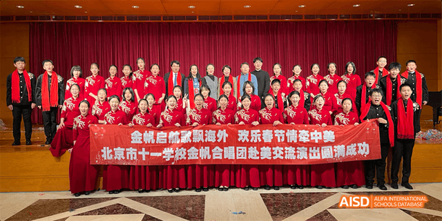 A large group of students from Beijing National Day School International Department posing with a red banner.