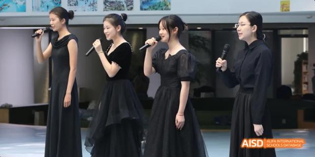 Students from Beijing National Day School International Department singing or performing on a stage.