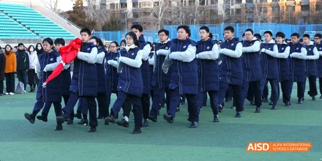 Students from Beijing National Day School International Department marching or performing a synchronized routine outdoors.
