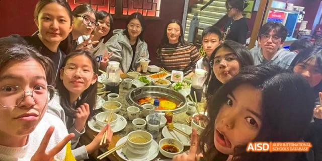 A group of students from Beijing National Day School International Department taking a selfie at a hot pot dinner.