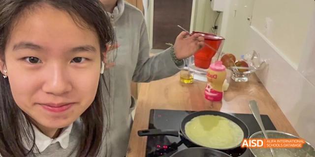 A student from Beijing National Day School International Department cooking on a small hot plate in a kitchen.