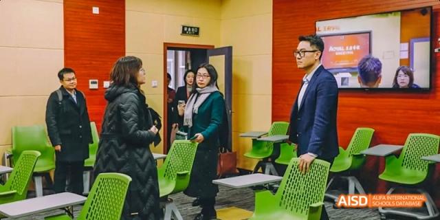 A photo showing students standing in a classroom and discussing something, at Beijing Royal School.