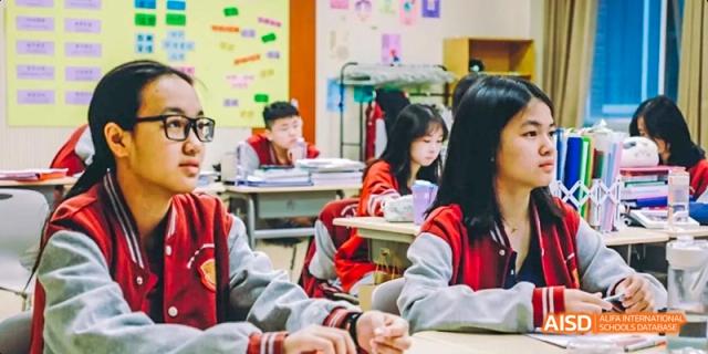 A photo showing students sitting in a classroom and doing a craft project, at Beijing Royal School.