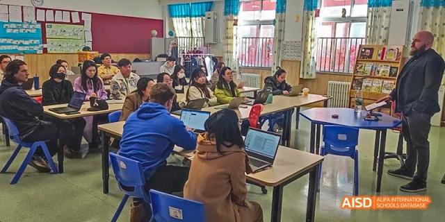 A photo showing students sitting on benches and eating food, at Beijing Royal School.
