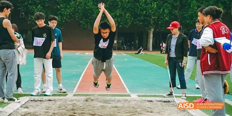 A photo showing a student doing a long jump, at Beijing Royal School.
