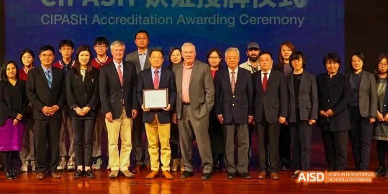 A photo showing a group of people posing for a photo at an award ceremony, at Beijing Royal School.