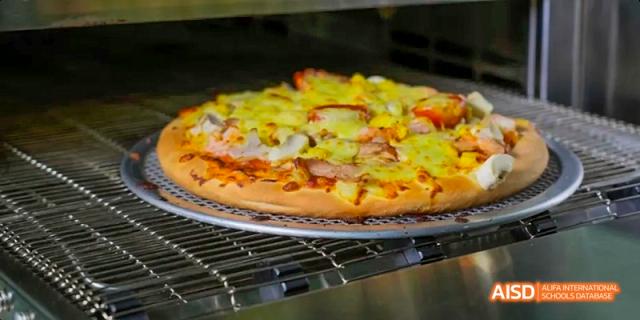 A photo showing a pizza with pineapples, at Beijing Royal School.