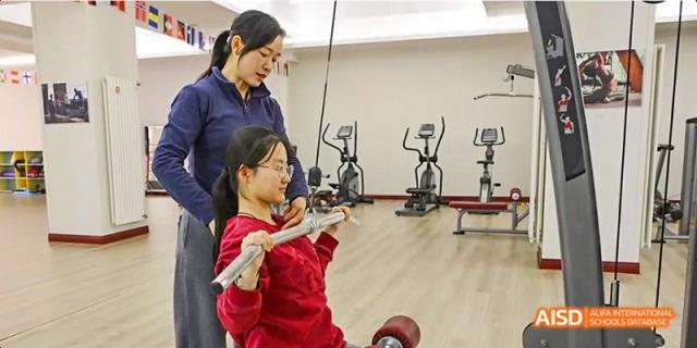 A photo showing a student exercising with a teacher, at Beijing Royal School.