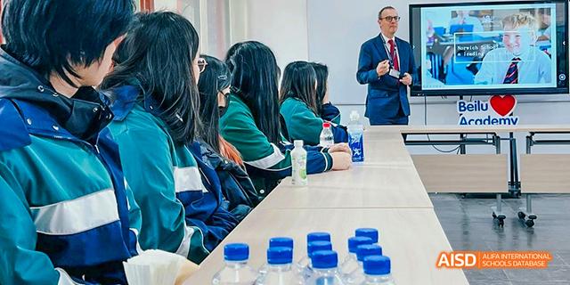 A group of students from Beilu Academy, sitting in a classroom and looking at some blue objects on their desks.