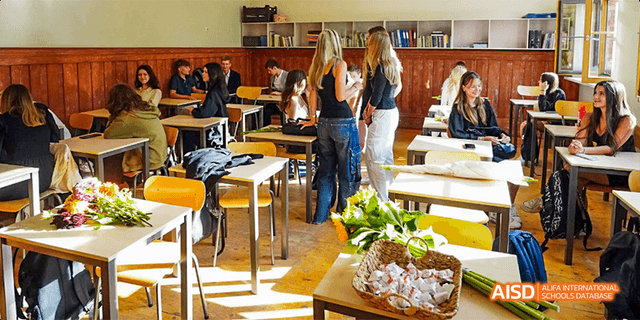 A close-up view of a baked good, possibly a cake, on a table in a classroom at Beilu Academy.