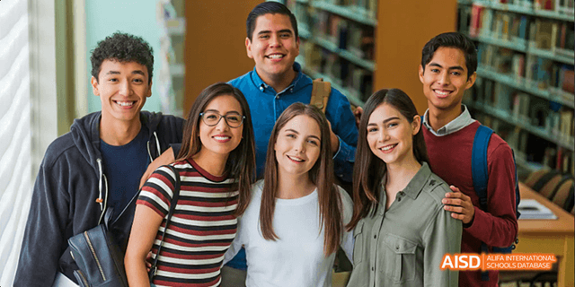 A group of diverse students from Beilu Academy, smiling and posing for a photo in a library.
