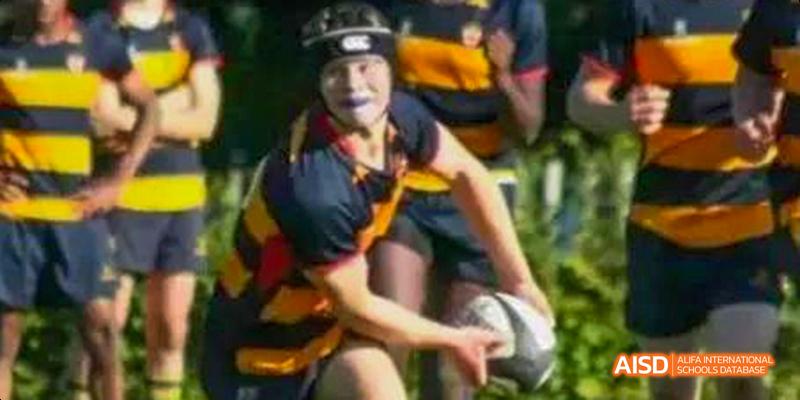 A student from Beilu Academy, in a yellow and black jersey, holding a rugby ball during a match.